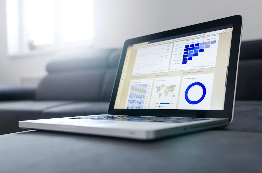 Open laptop displaying analytical graphs and charts on the screen, placed on a dark grey couch in a bright room.